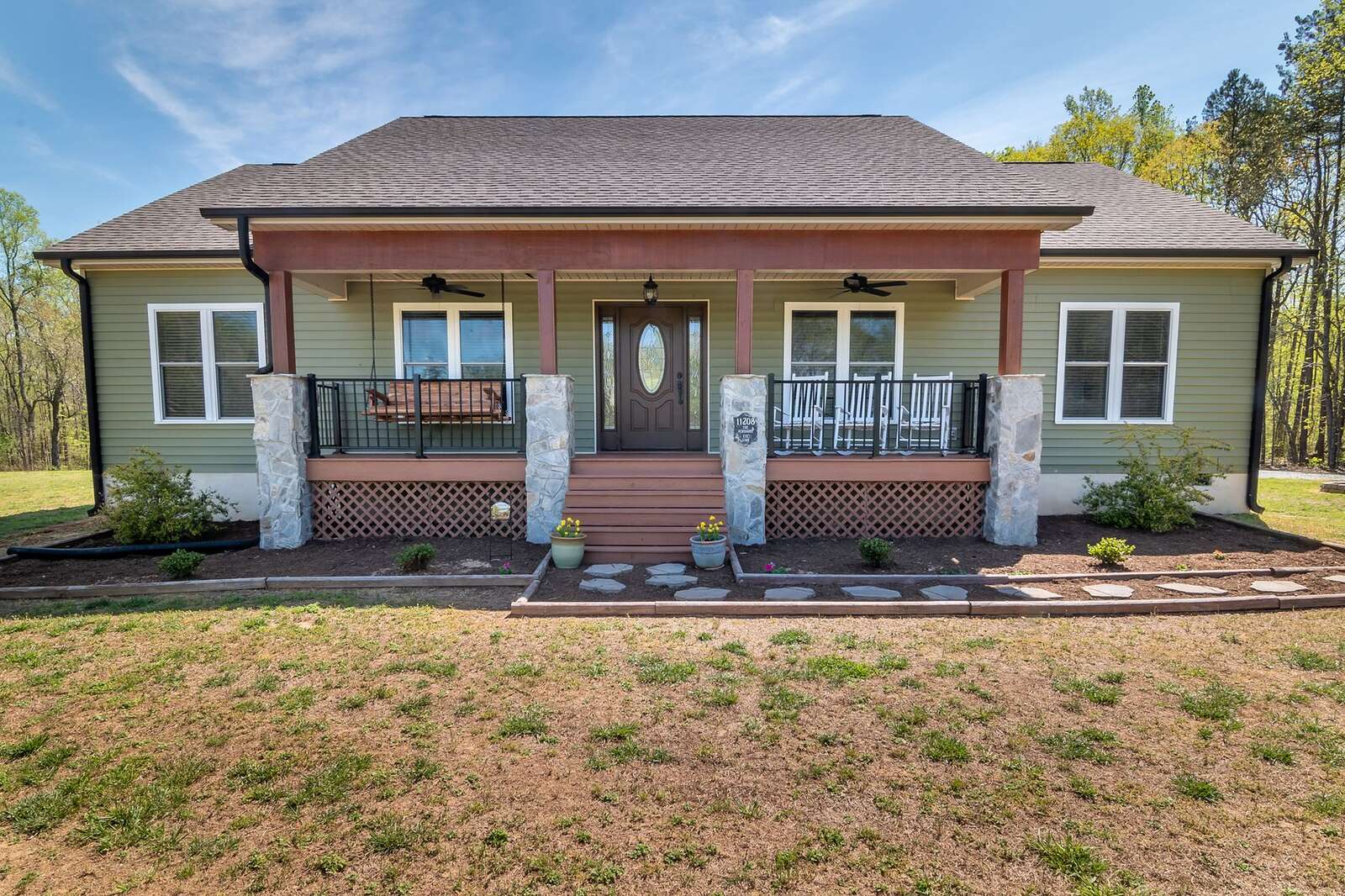 A green wood-frame bungalow with a wide front porch