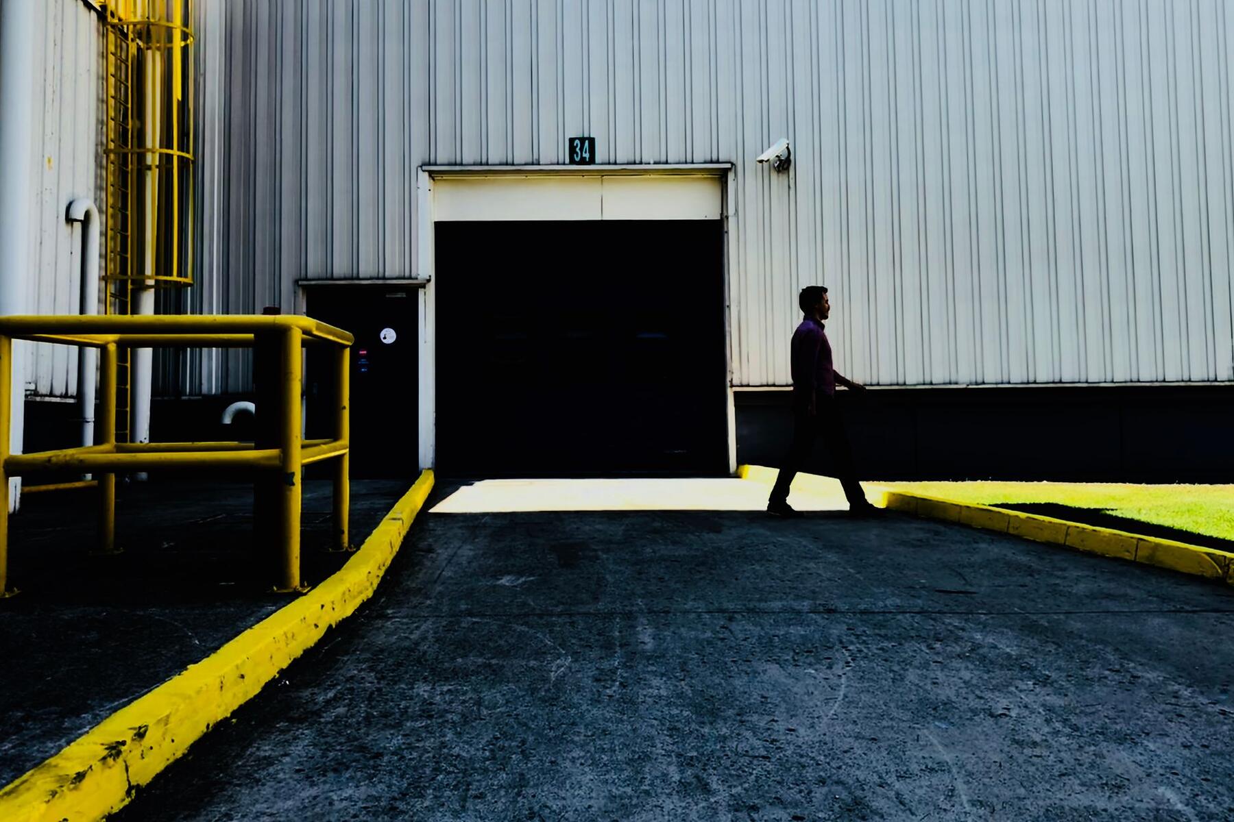 A person walking past a large roll-up door at a warehouse loading dock